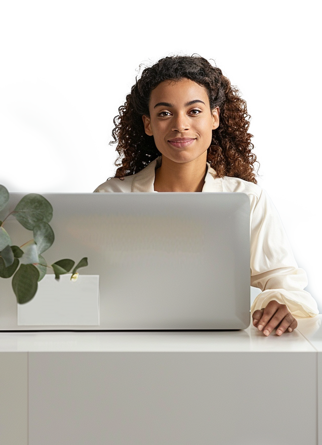 A woman, smiling, sitting at a computer, in a receptionist setting.