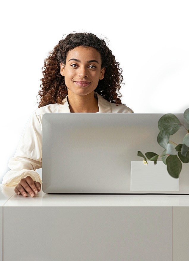 A woman, smiling, sitting at a computer, in a receptionist setting.